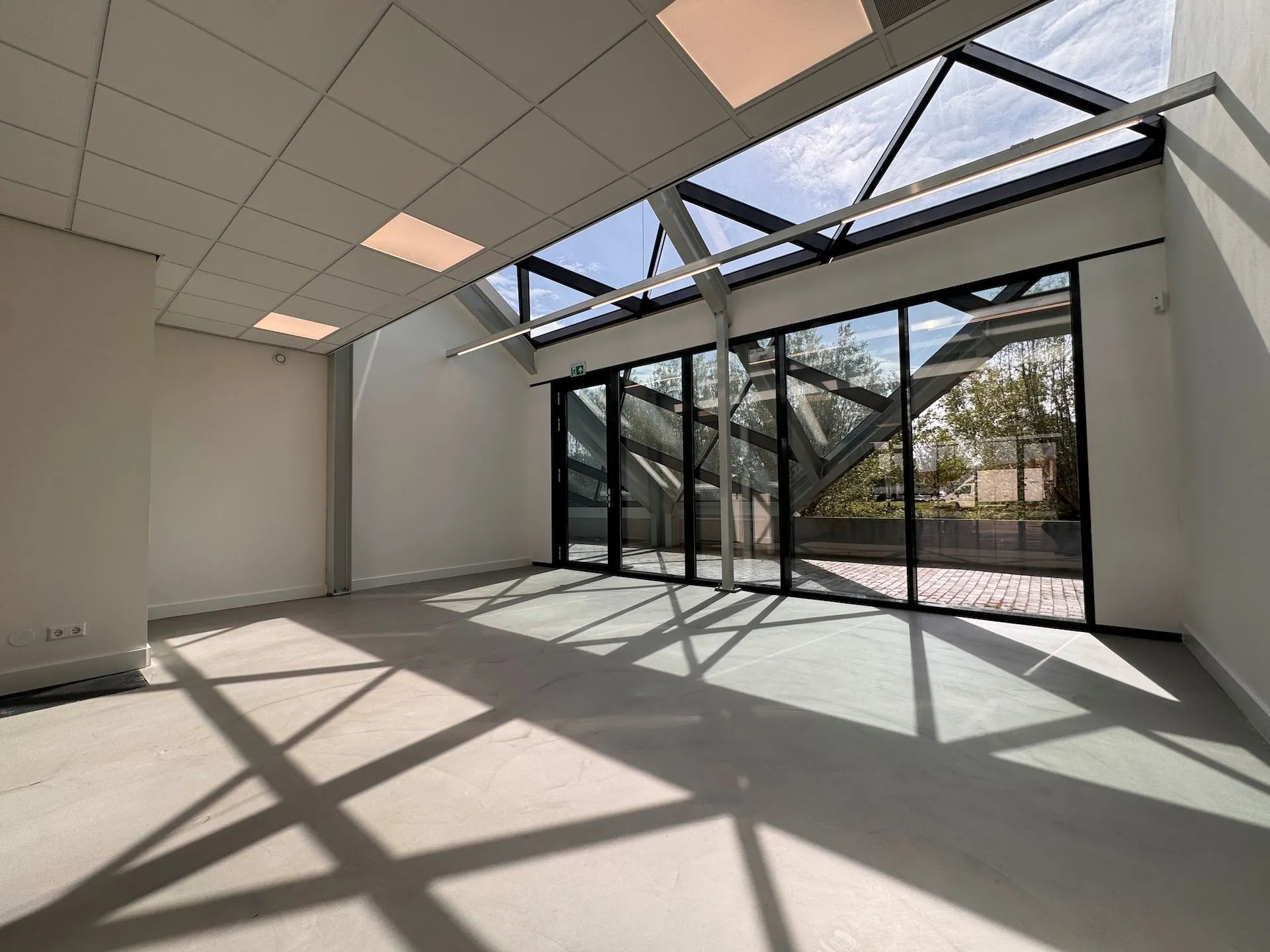 Licht en modern kantoorruimte in Mart Stamhof met glazen gevel en zicht op buitenterras.